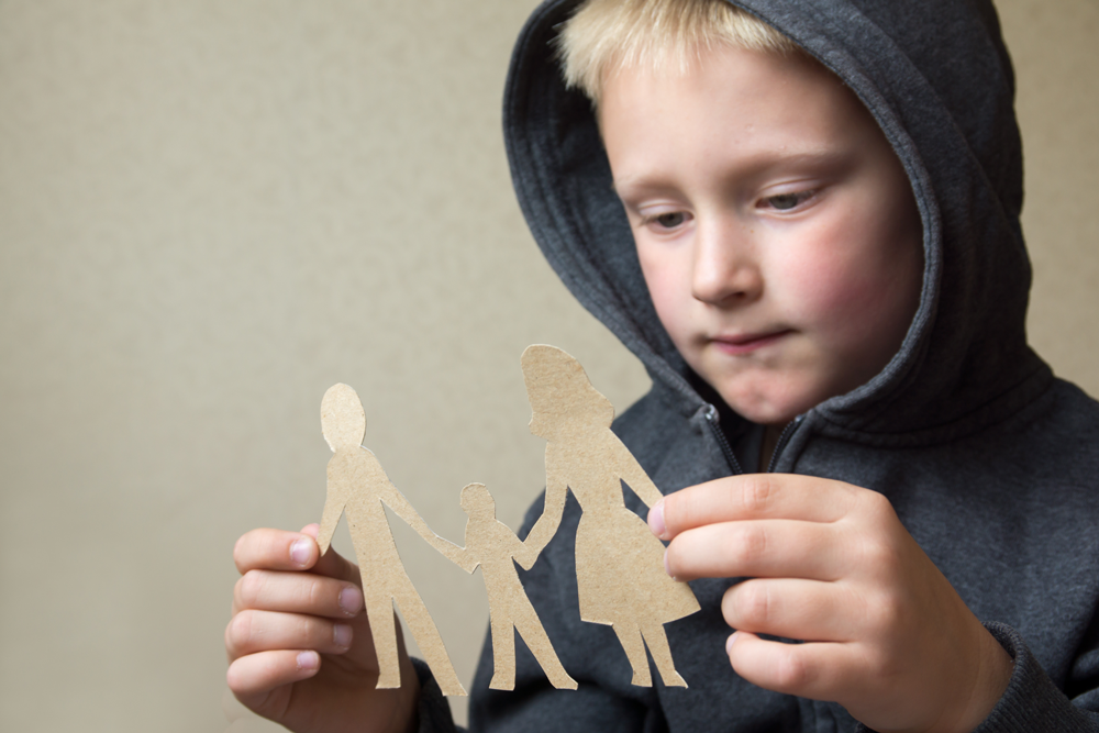 image of a child holding a paper cutout of a family